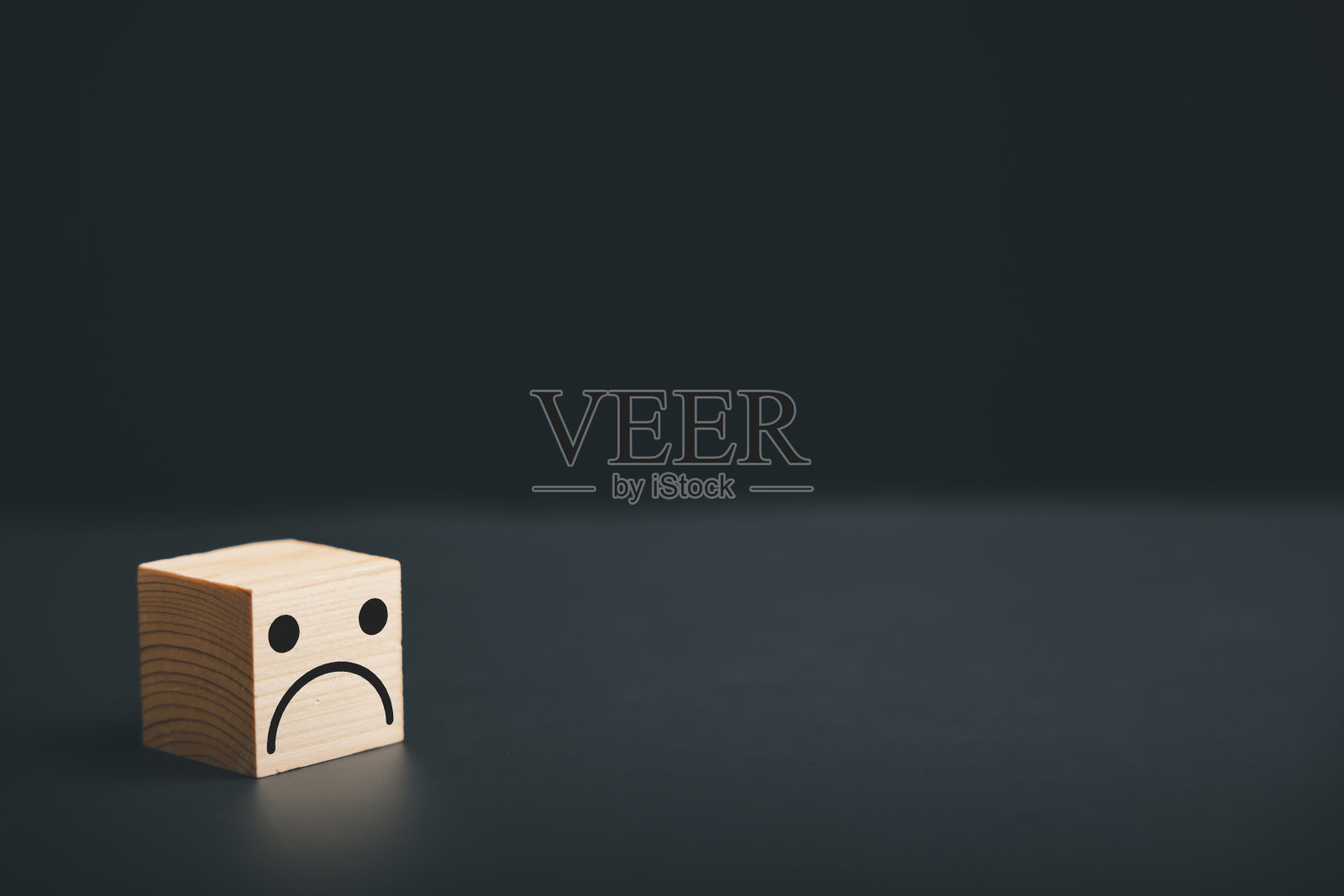 一个黑色背景的木块立方体上的皱眉图标照片摄影图片