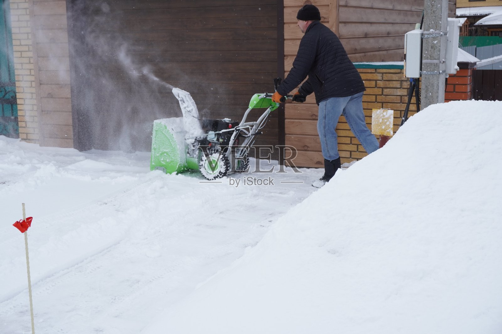冬天,一个人在房子的院子里打扫雪,一个人用吹雪机打扫雪照片摄影图片
