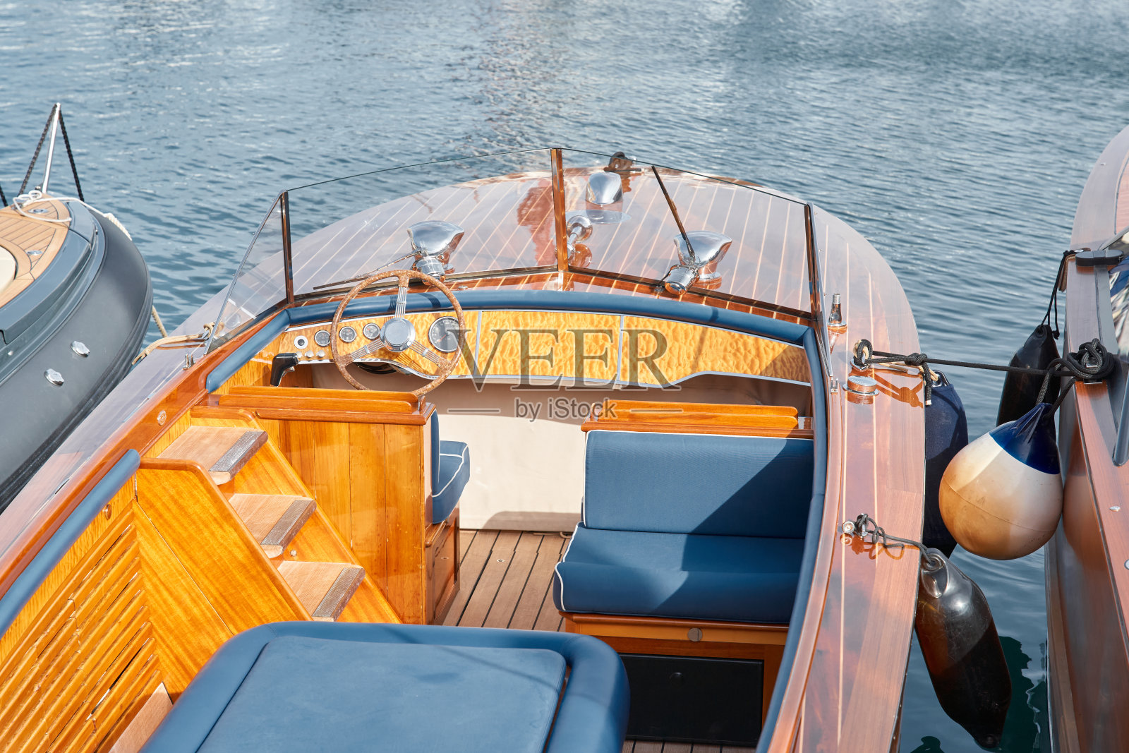 在阳光明媚的日子里,一艘昂贵的摩托艇的开放式柚木甲板上的休闲区特写,摩纳哥游艇展,大型游艇展,财富生活,桌椅照片摄影图片