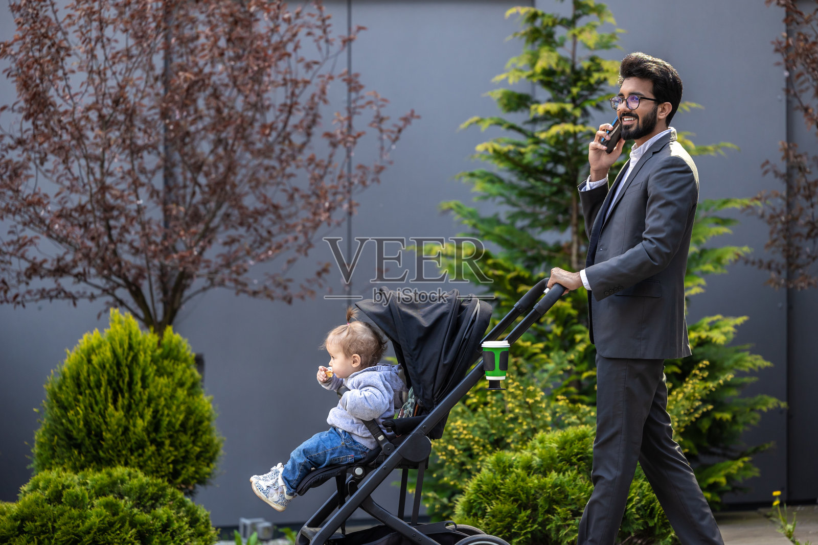 年轻优雅的男人推着婴儿车在打电话照片摄影图片