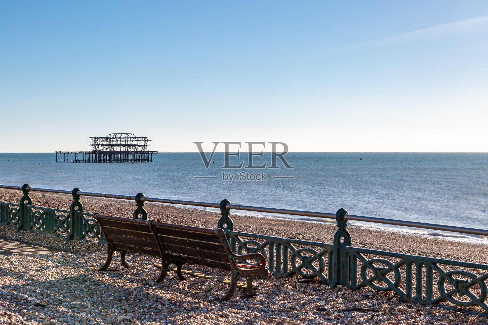 在苏塞克斯海岸的布莱顿,鹅卵石被冲到长凳周围的散步道上照片摄影图片