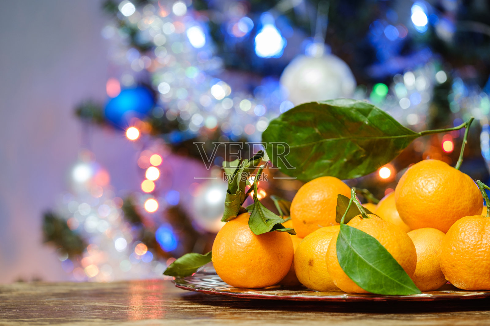 桌子上的橘子以圣诞树为背景照片摄影图片