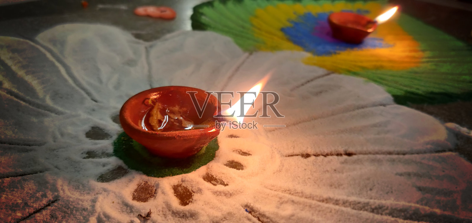 印度传统节日排灯节,Navratri,庆祝一个发光的Diya灯虔诚的火焰在白花和彩色rangoli设计的水平背景照片照片摄影图片