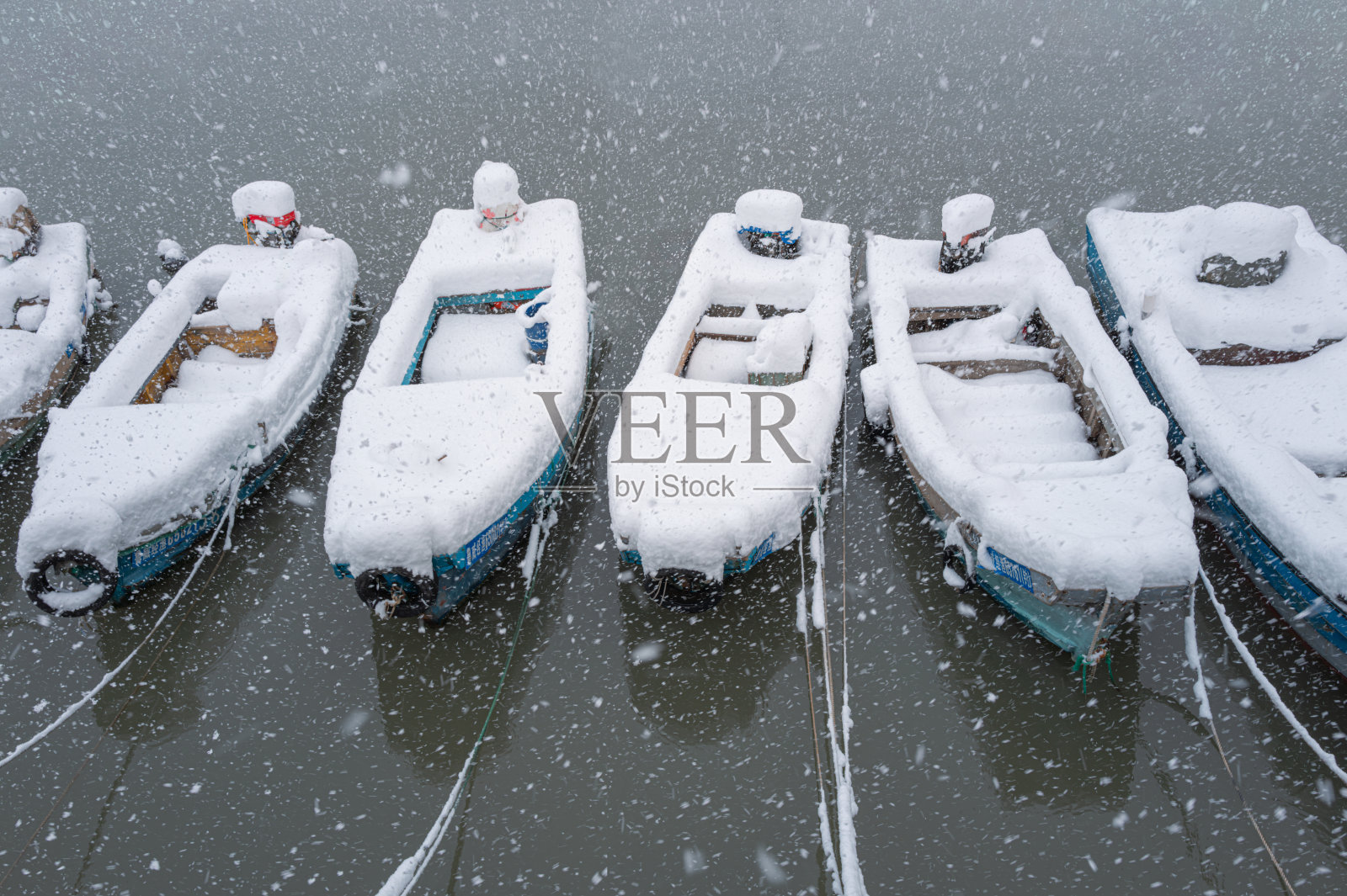大雪过后,小木船停泊在渔港里照片摄影图片