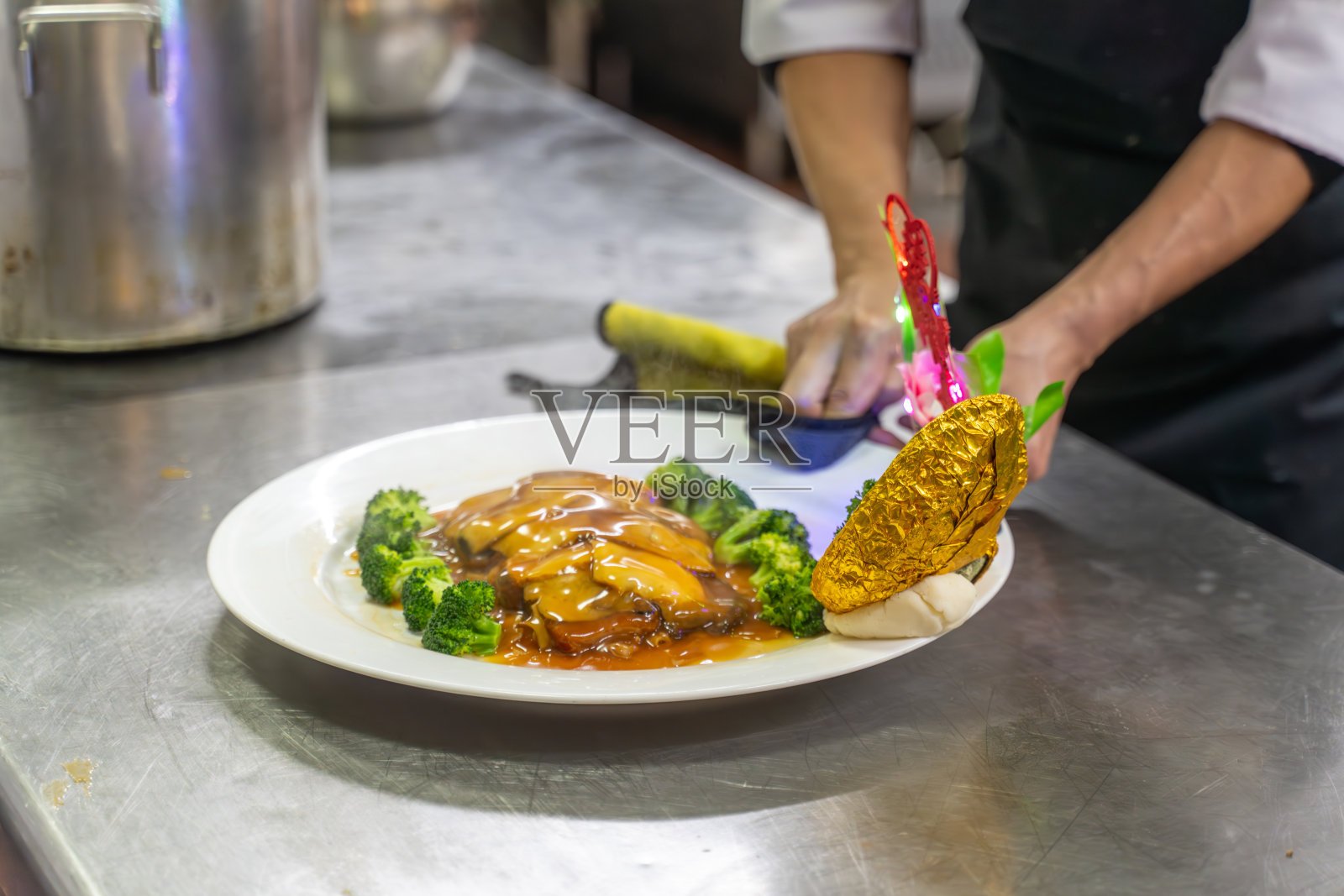 厨师的手正在用鲍鱼片做菜照片摄影图片