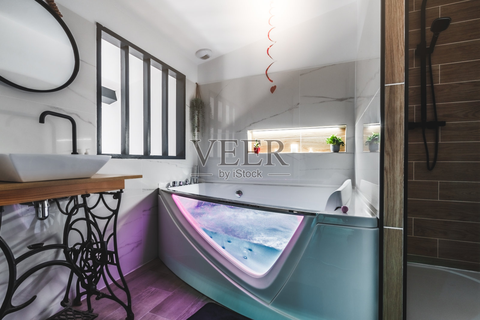 豪华的现代浴室在一个舒适的阁楼与照明水疗按摩浴缸充满水照片摄影图片