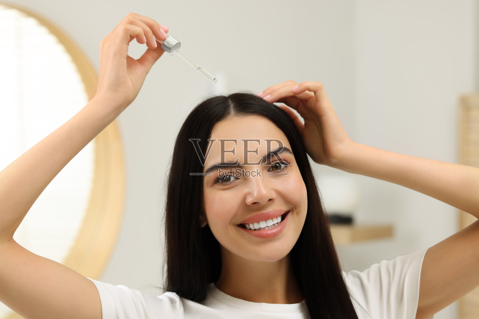 美女在室内涂抹护发精华液。美容产品照片摄影图片