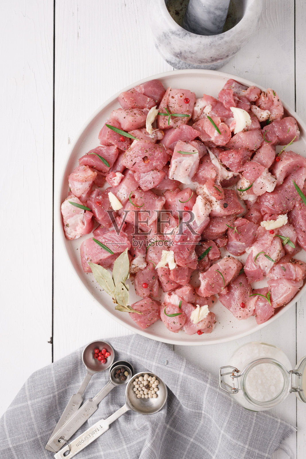 一块新鲜的生猪肉和香料放在白色的木桌上。香料肉照片摄影图片