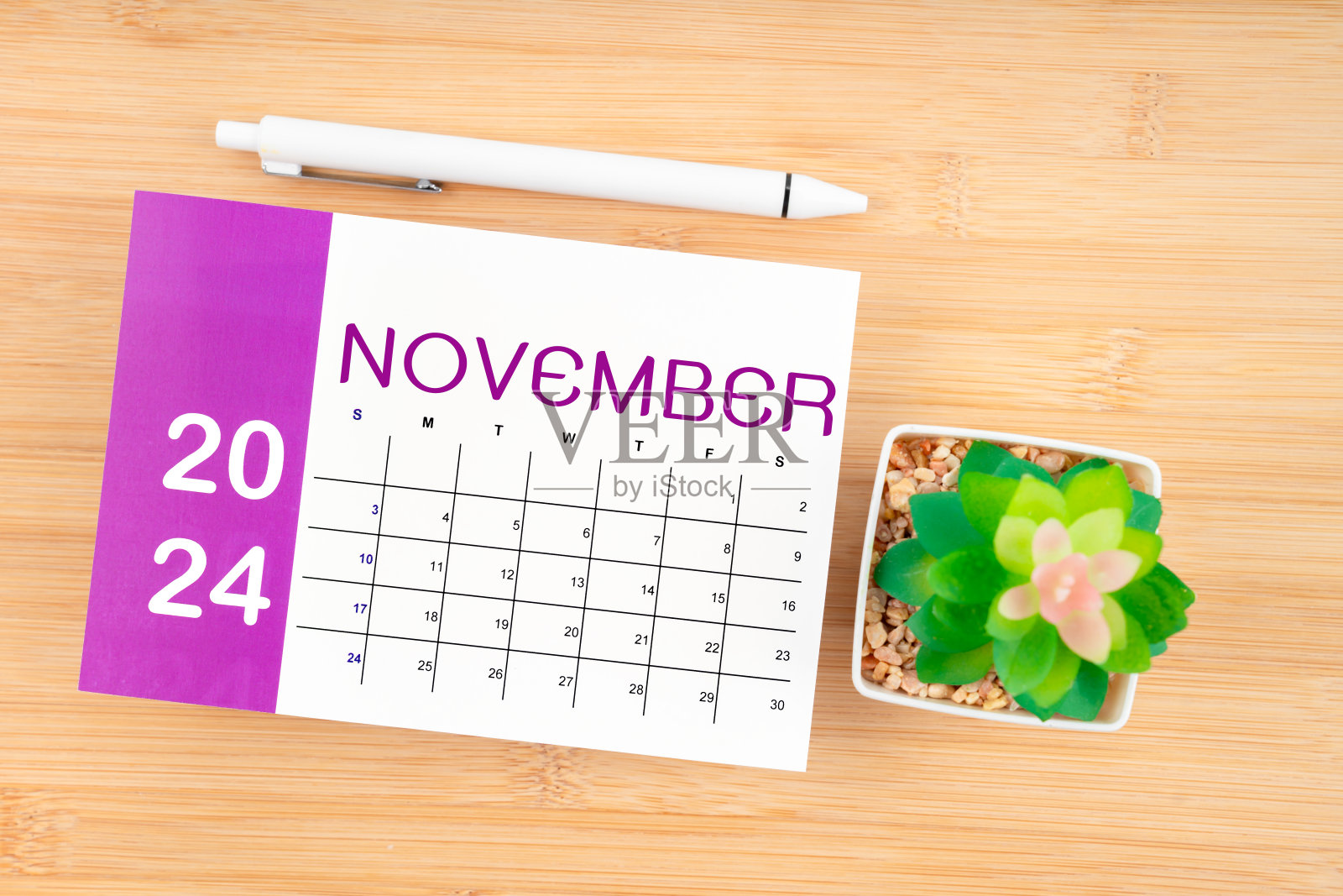 2024年11月日历页和笔带花盆。照片摄影图片