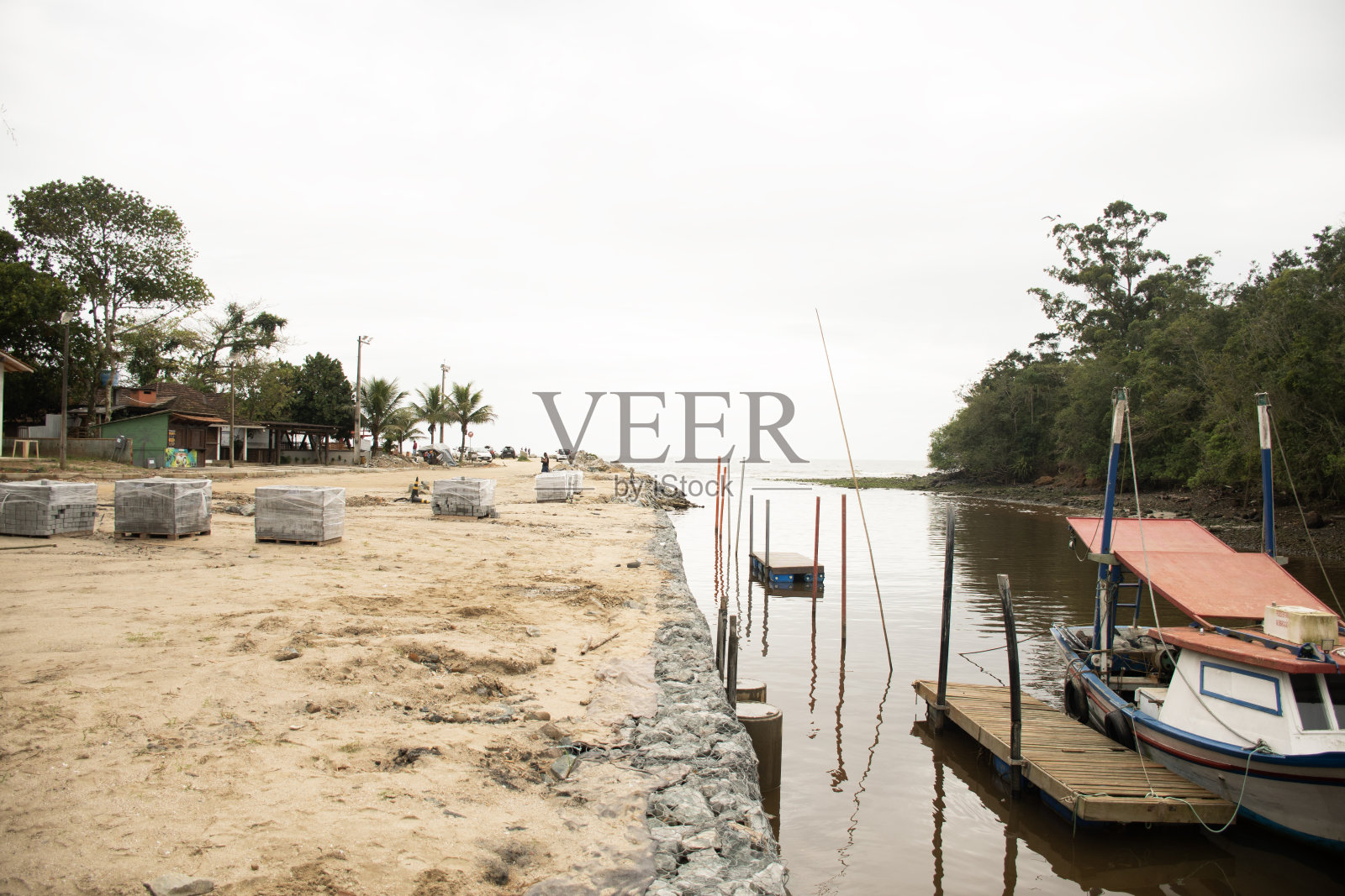 鱼船在平静的水河滨在一个阴天的海滩照片摄影图片