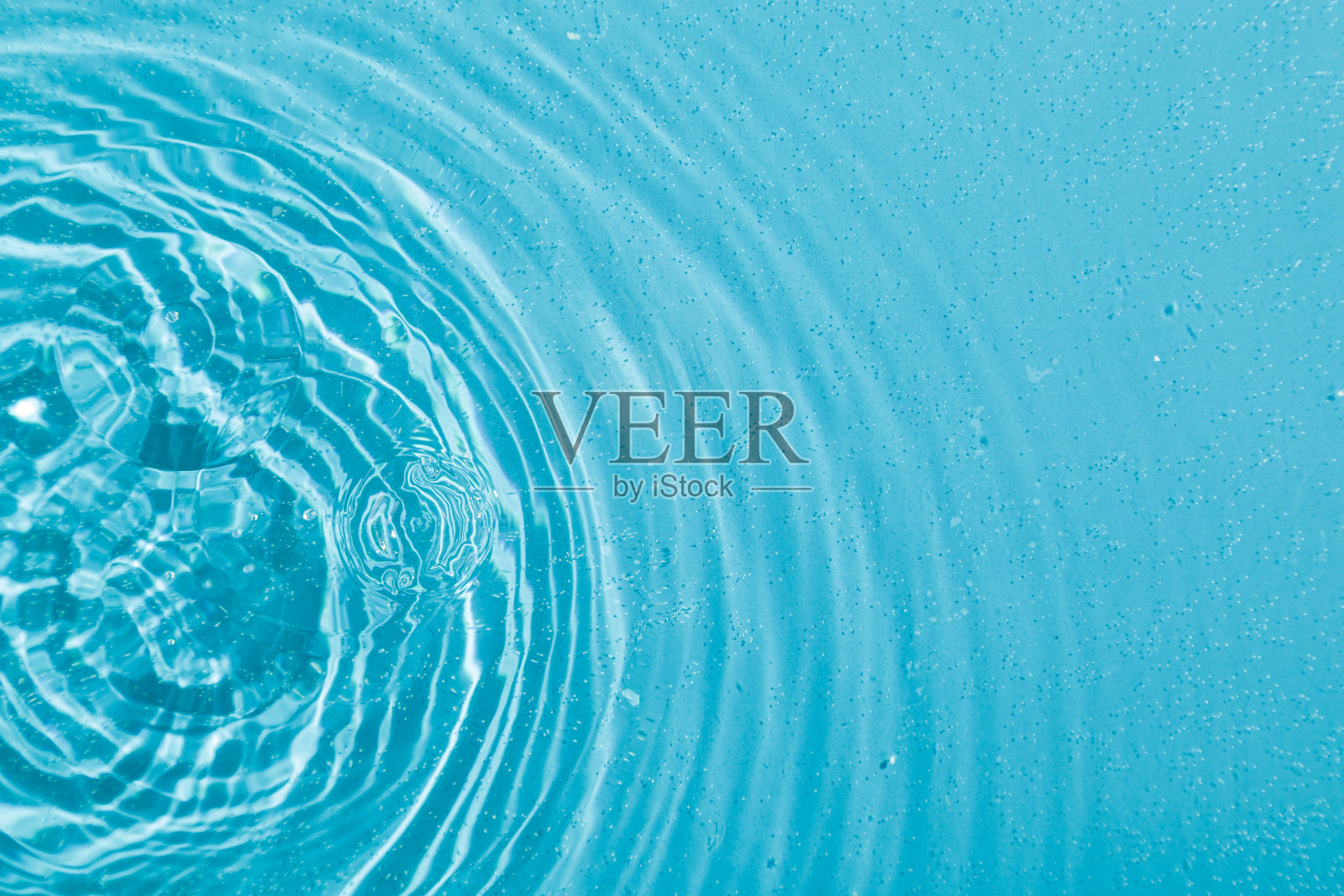 水滴在水面上,蓝色背景上有圆圈照片摄影图片