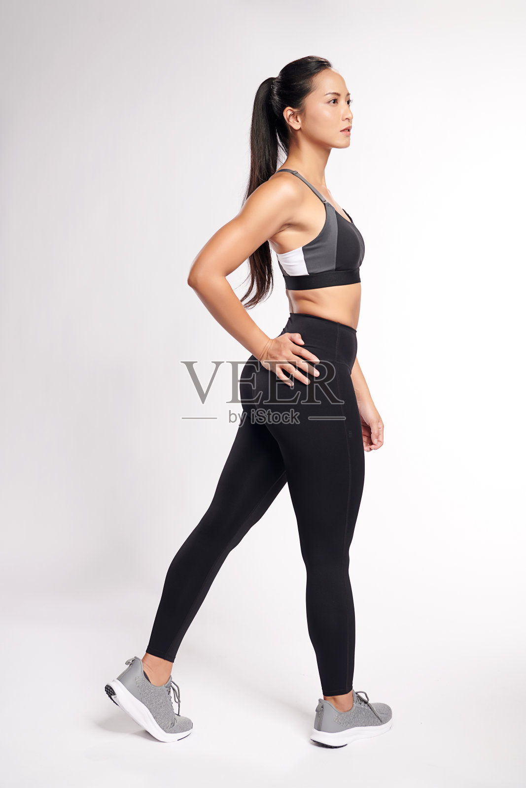 一位亚洲妇女穿着白色背景的运动服在锻炼。照片摄影图片