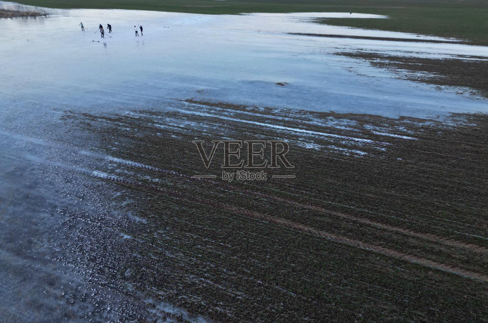 被洪水淹没的田地变成溜冰场,儿童在水坑中玩耍照片摄影图片