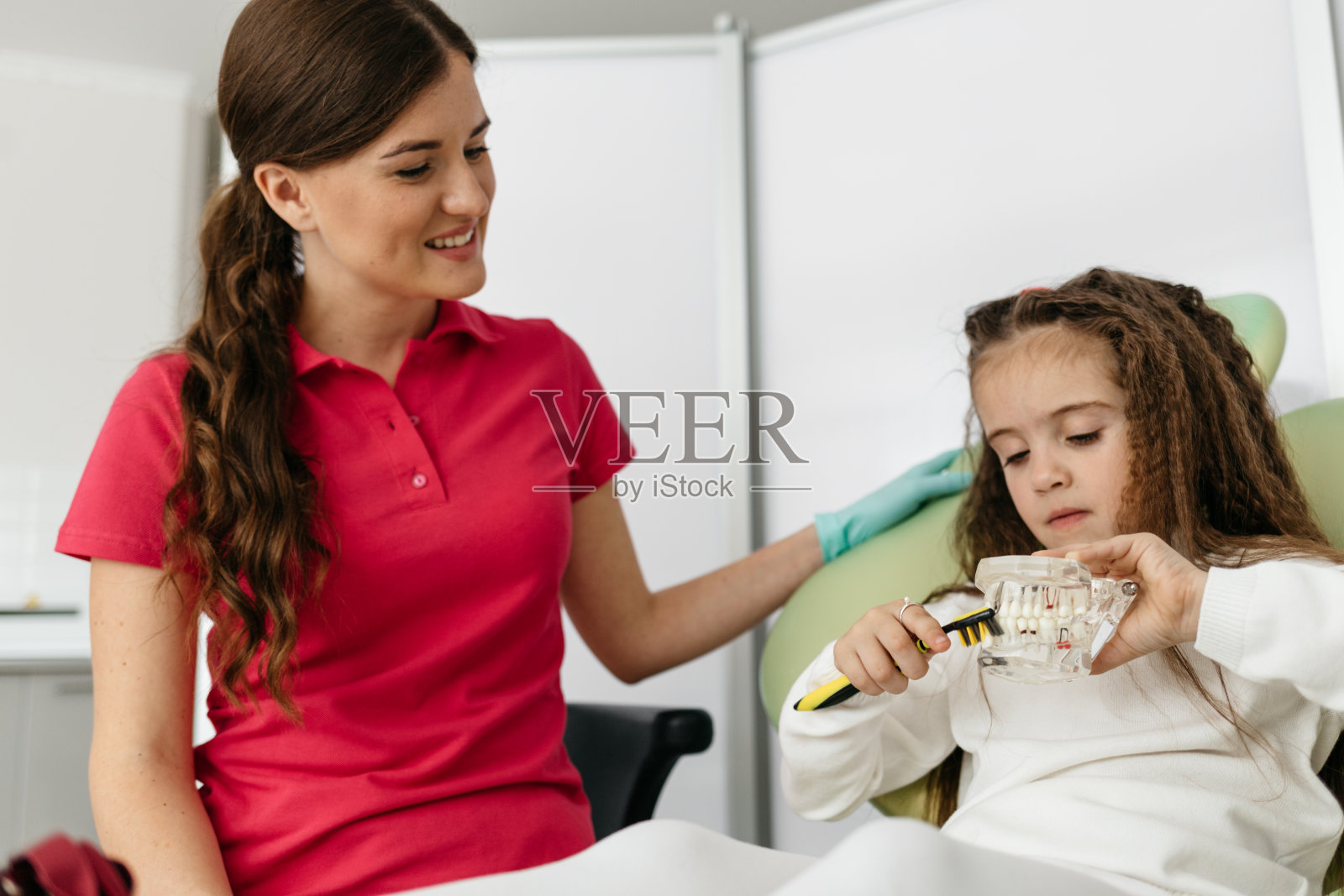 一个女孩在牙医的办公室里示范如何刷牙照片摄影图片