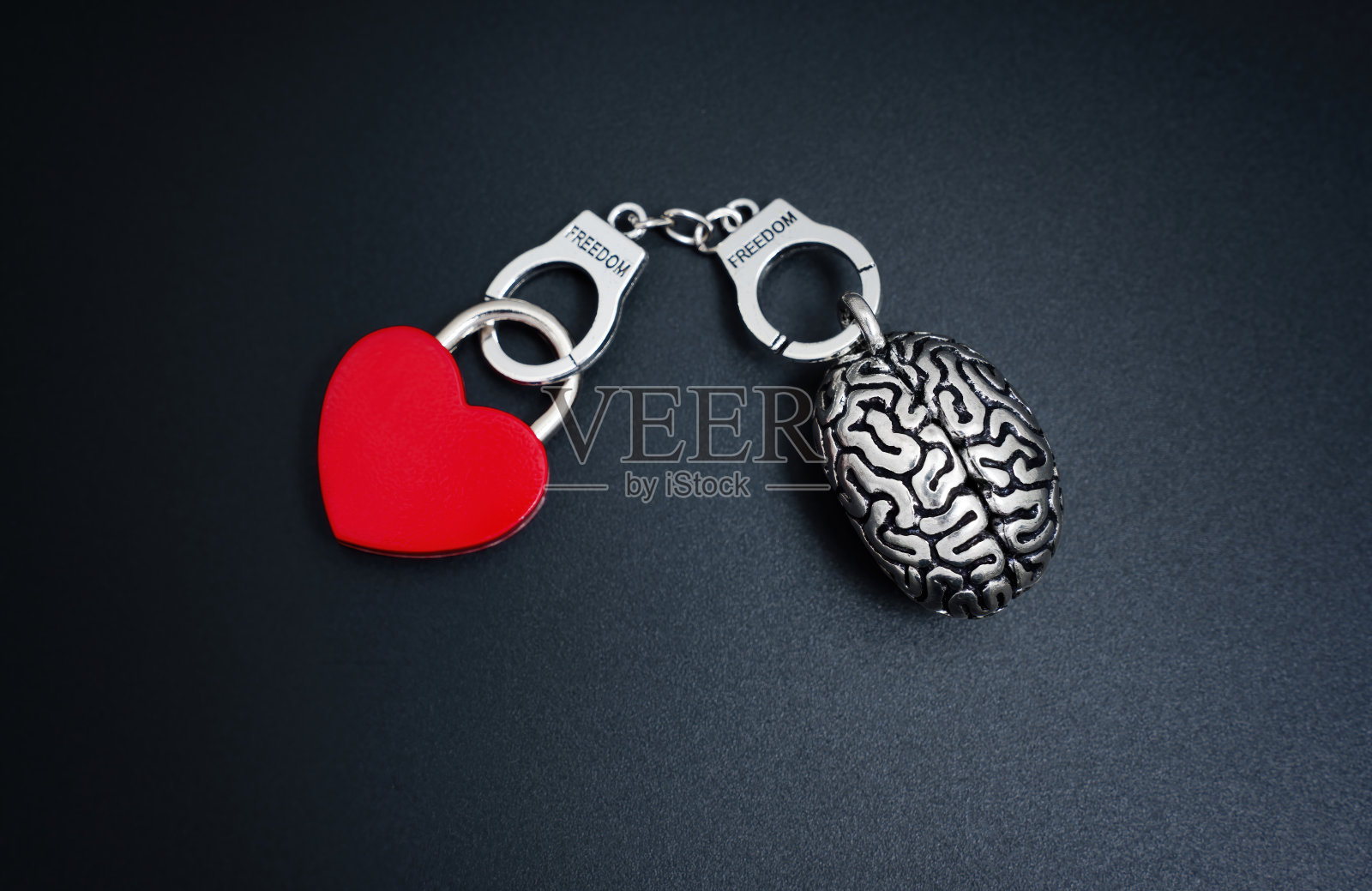 钢制人脑模型和用镣铐连接的心形挂锁照片摄影图片