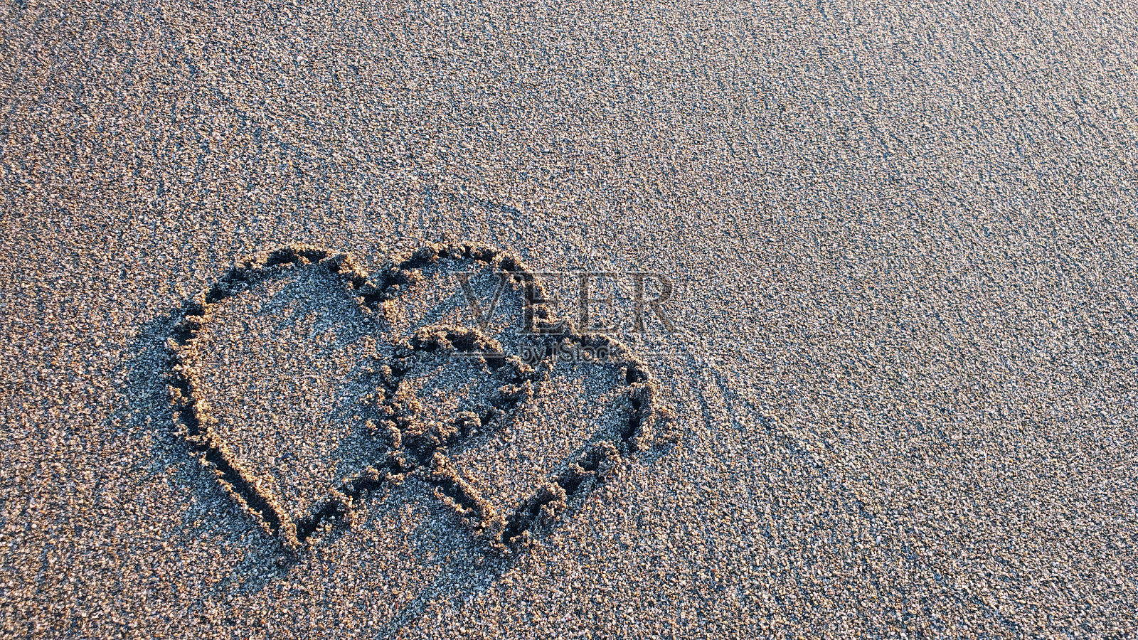 两颗心画在天堂海滩的棕色沙滩上照片摄影图片