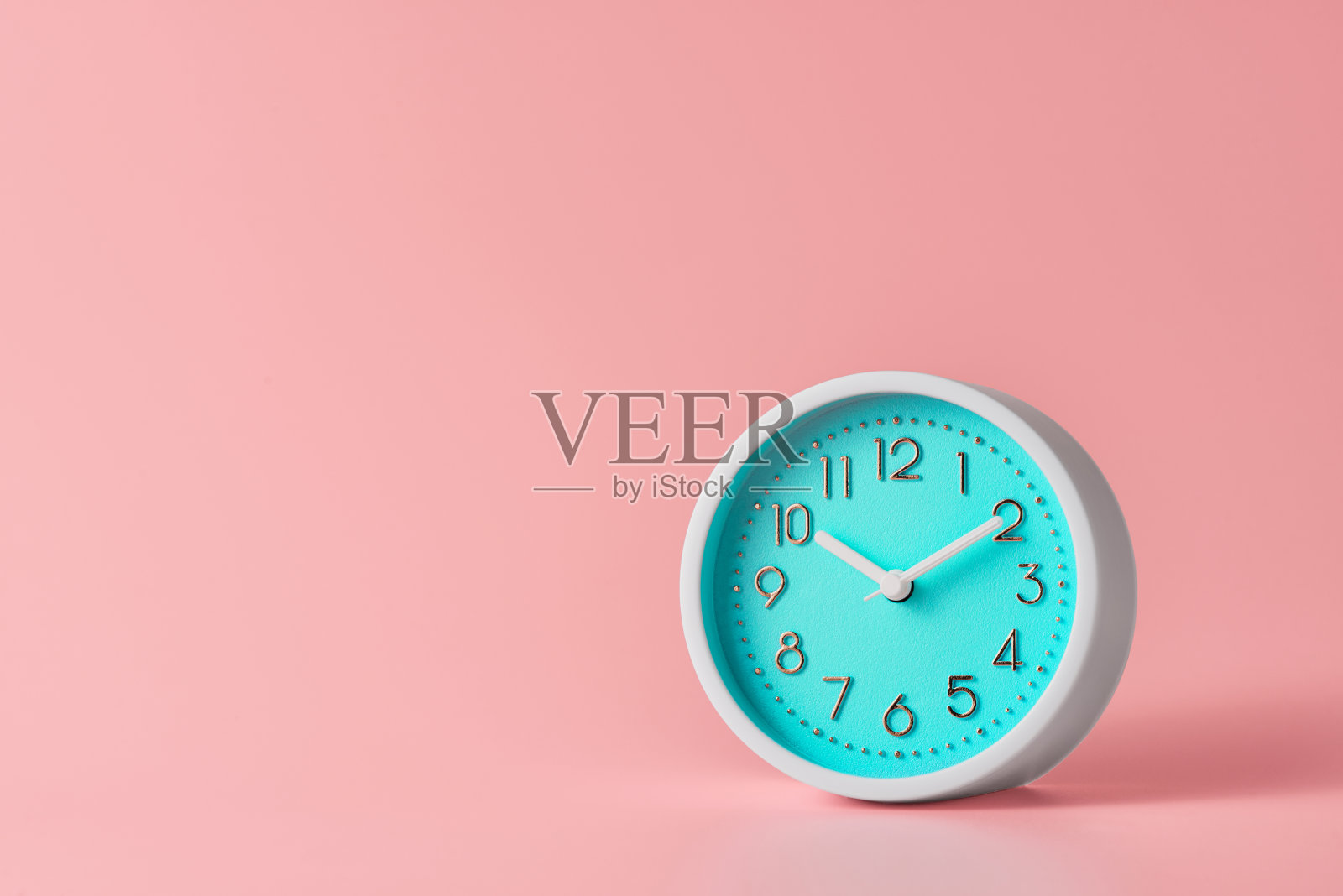 圆形模拟闹钟在一个粉红色的背景与复制空间。低角度前视图。照片摄影图片