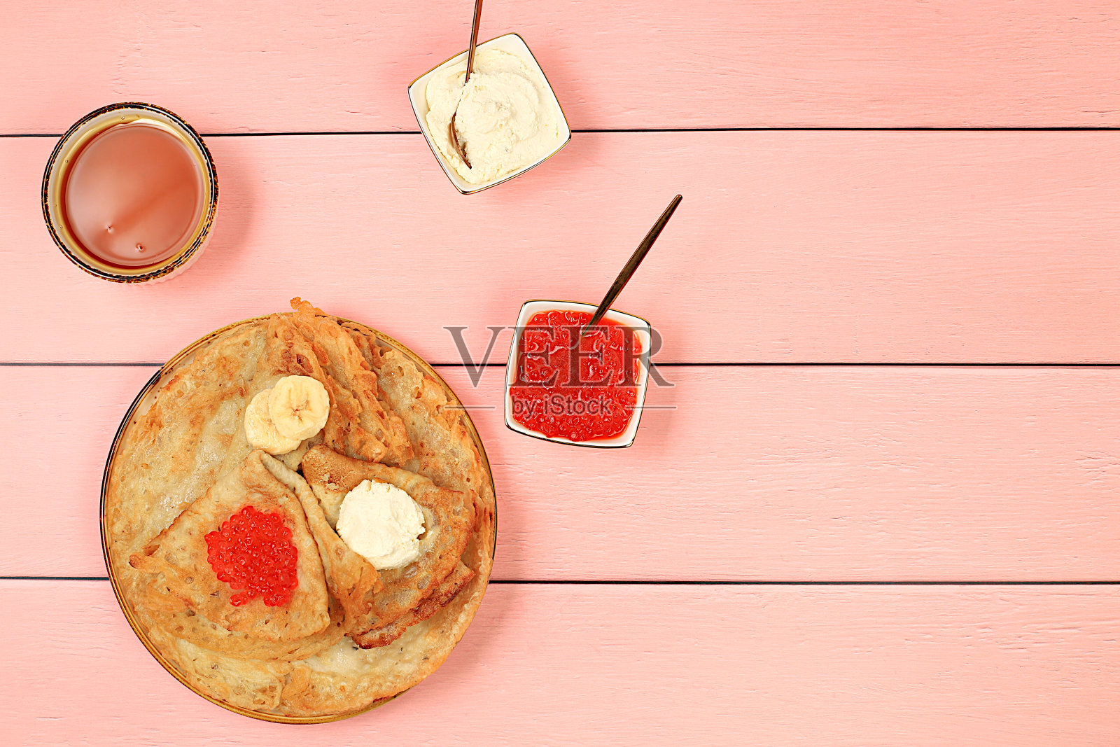 美味的俄罗斯煎饼配上红鱼子酱、软奶酪凝乳、香蕉和蜂蜜,摆在木桌上。食材健康早餐,嘉年华概念,民族传统美食,照片摄影图片