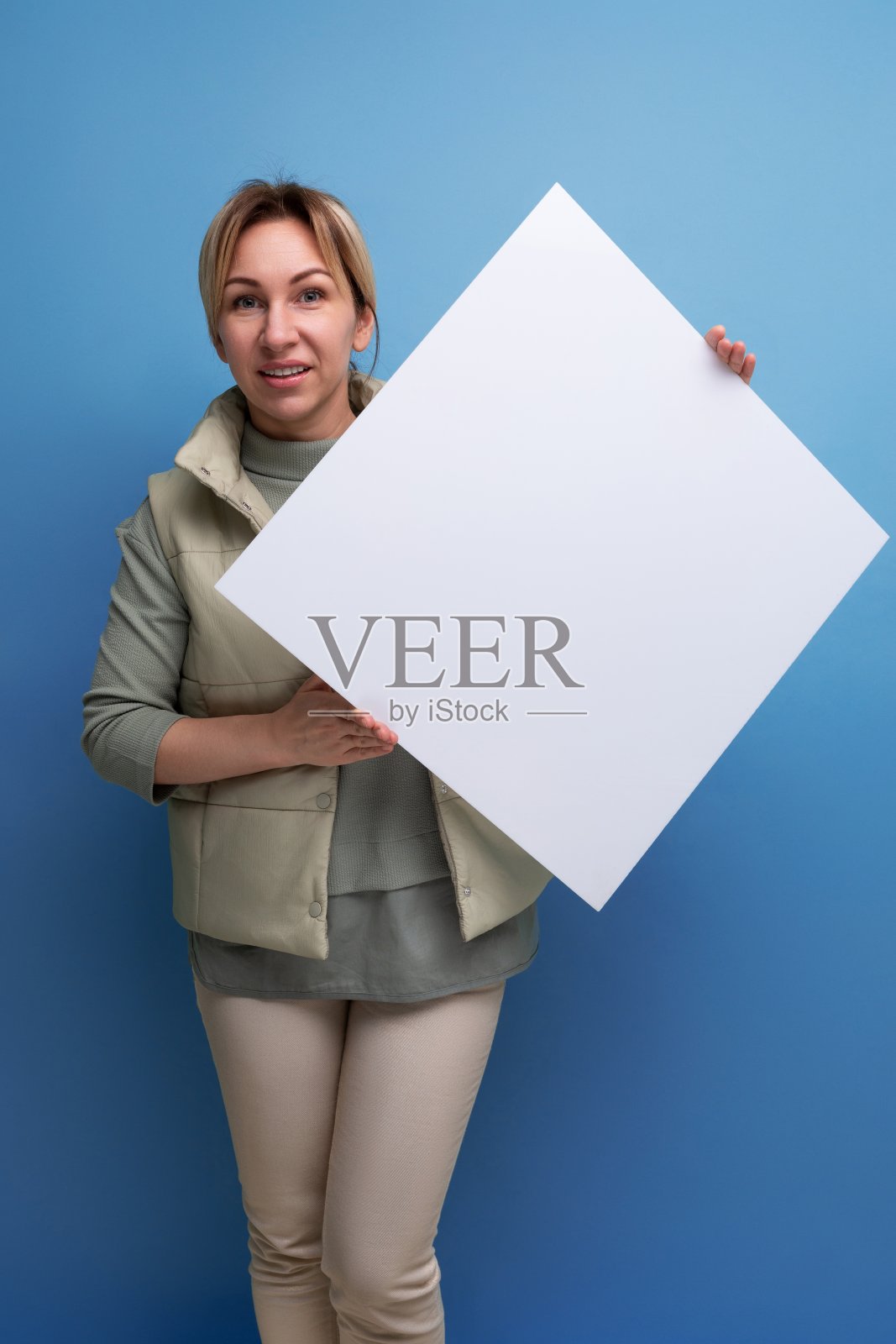 年轻的金发女子拿着一张海报,上面有一个广告模型照片摄影图片