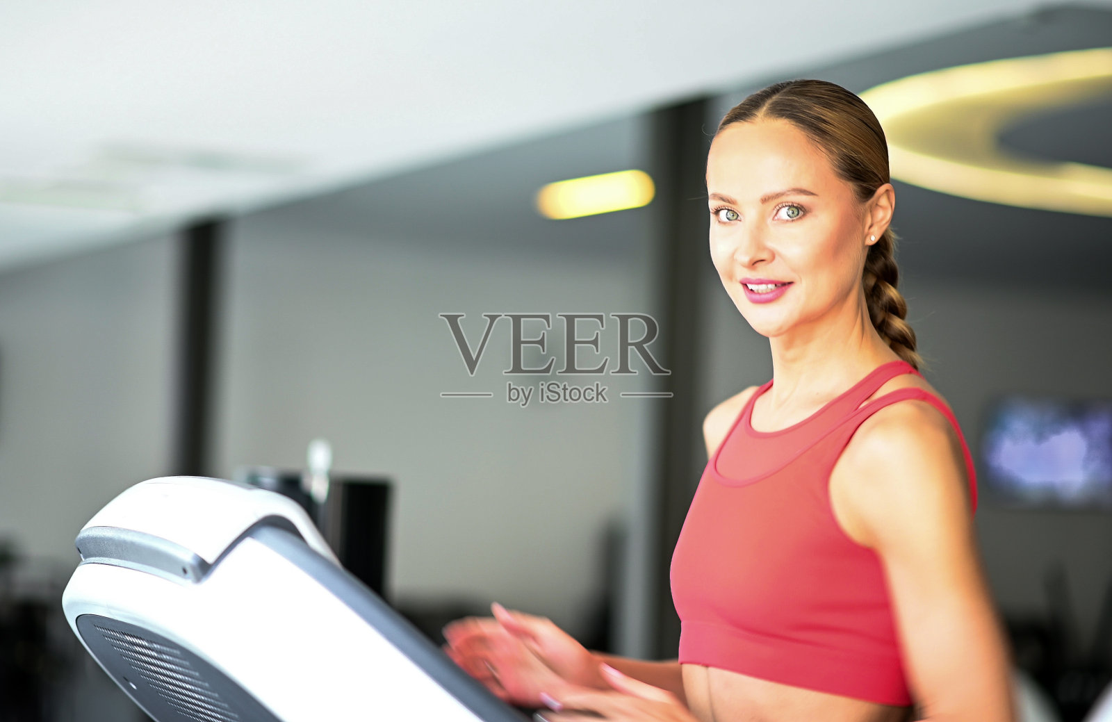 年轻的运动美女在健身房的跑步机上训练照片摄影图片
