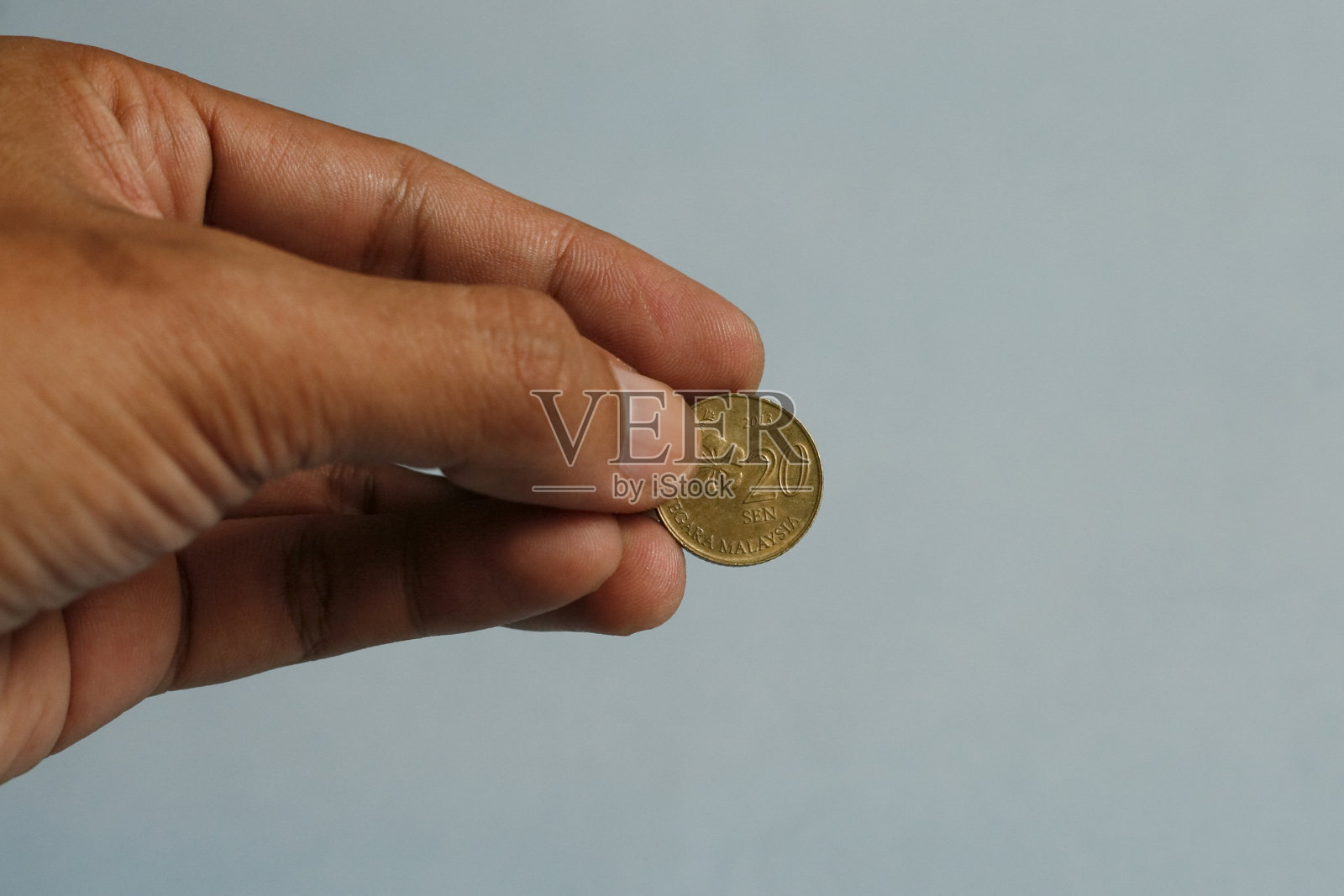 近距离的手拿着马来西亚的20分硬币。慈善组织的概念。照片摄影图片