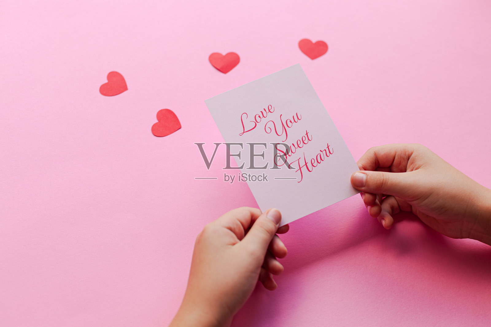 两只手捧着一张纸,上面写着“我爱你”甜蜜的花朵照片摄影图片
