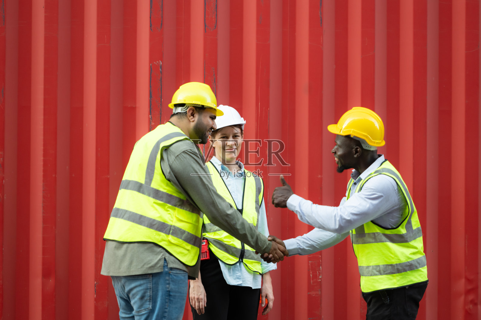 一群集装箱堆场工人在集装箱仓库前休息时互相问候。照片摄影图片