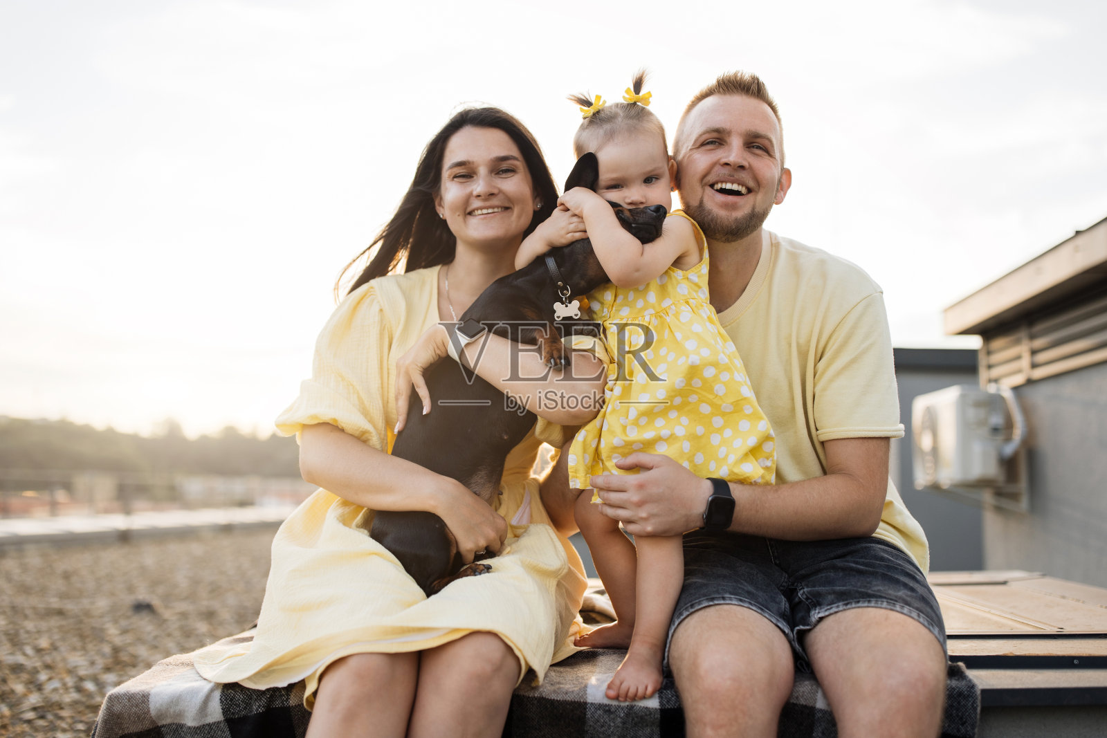 夕阳下,一家人带着狗在格子格子上放松照片摄影图片