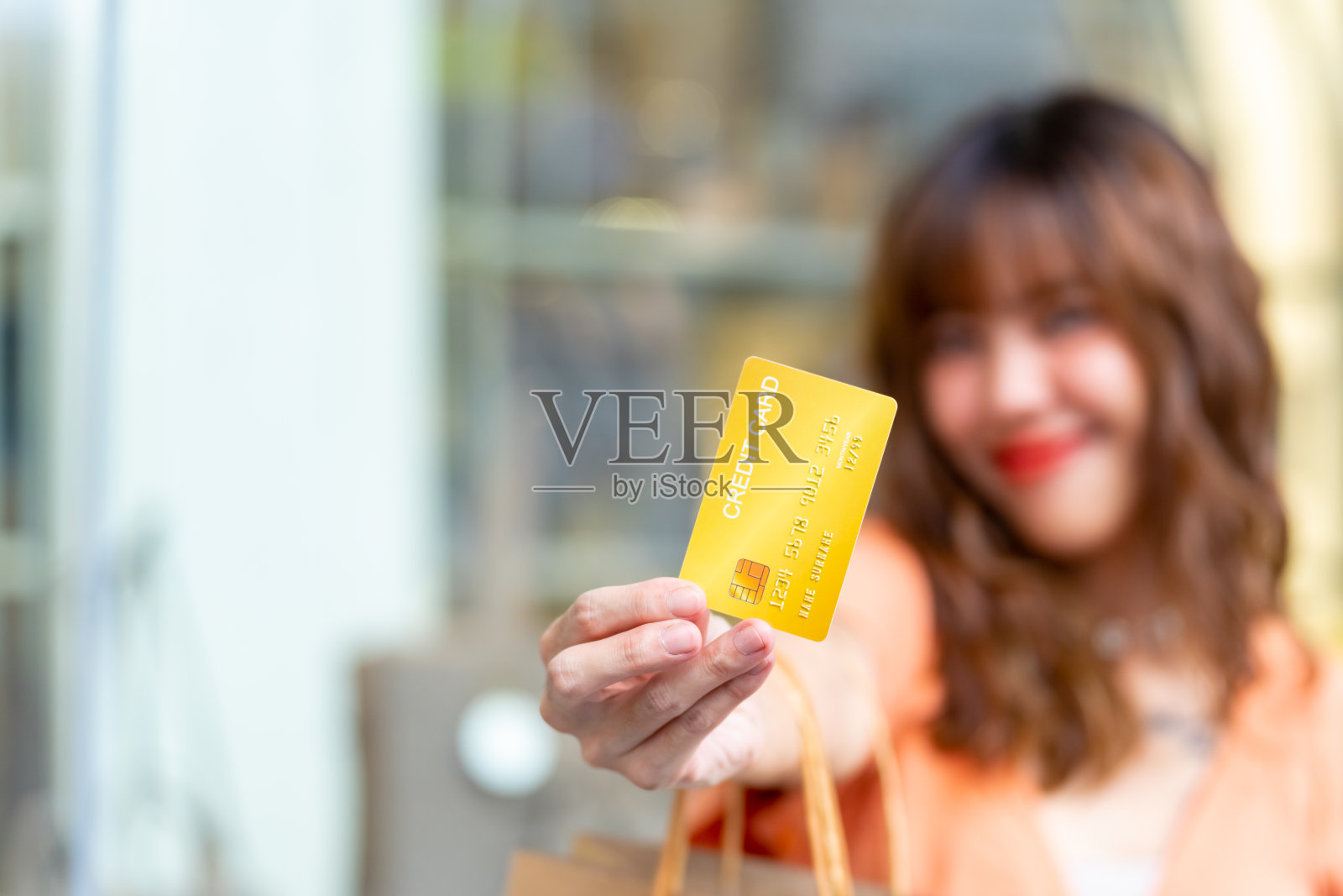 年轻的亚洲妇女在购物中心拿着信用卡的肖像。照片摄影图片