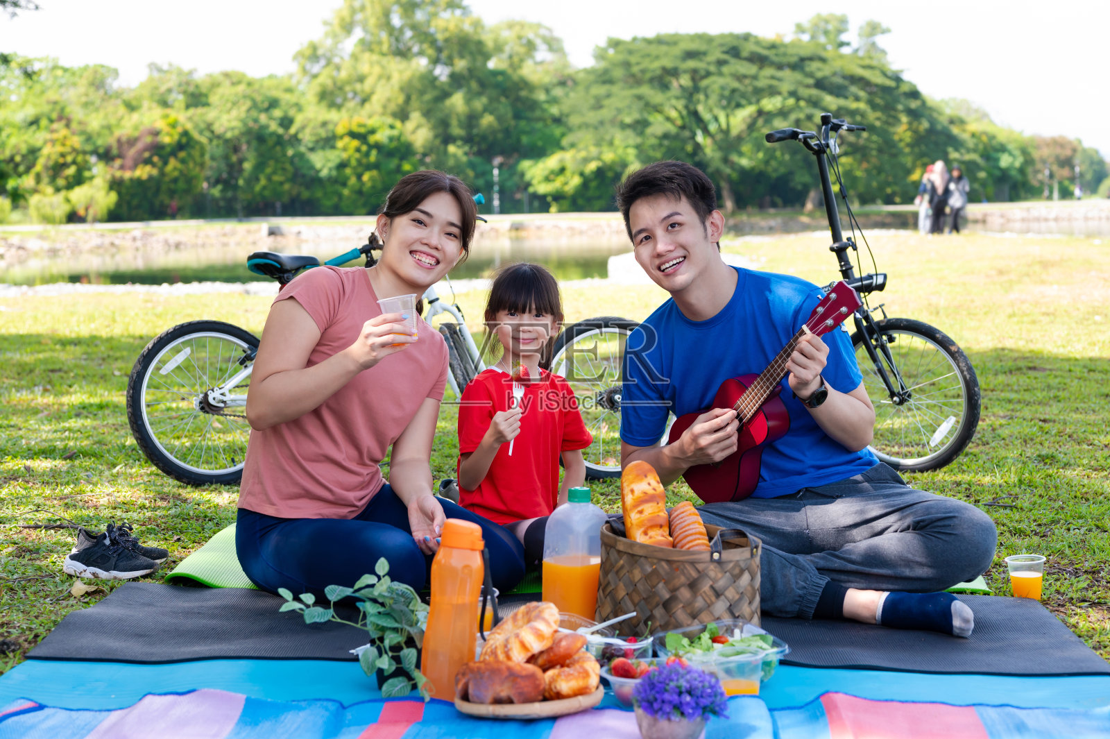 年轻的亚洲家庭喜欢在周末野餐时唱歌和弹奏尤克里里照片摄影图片