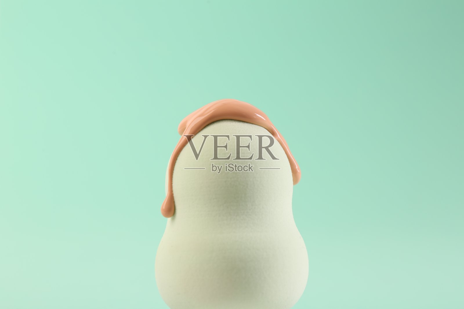 白色化妆海绵与皮肤基础在绿松石背景,特写照片摄影图片