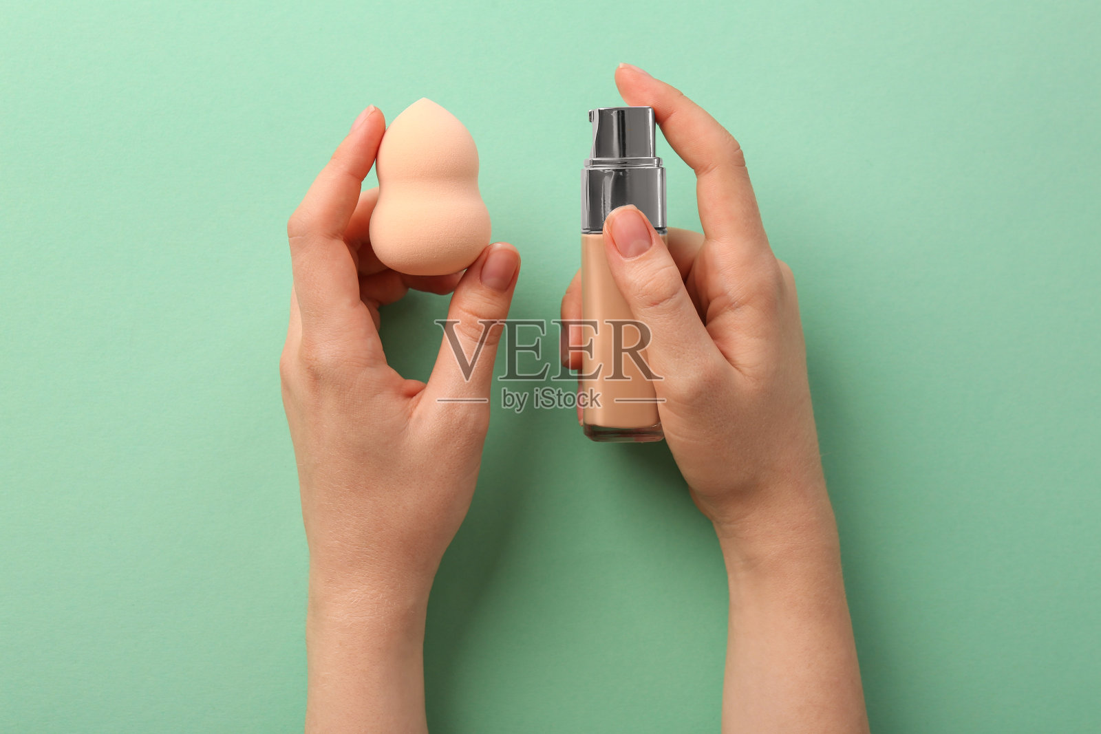 女子用化妆海绵和皮肤粉底,薄荷色背景,俯视图照片摄影图片