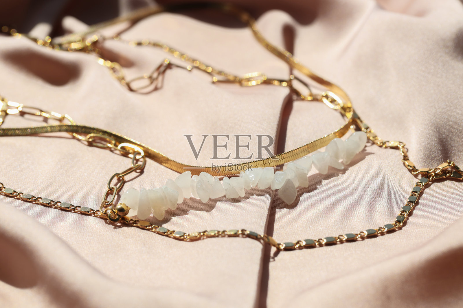 淡粉色布料上镶有宝石的金属链,特写。奢华的珠宝照片摄影图片