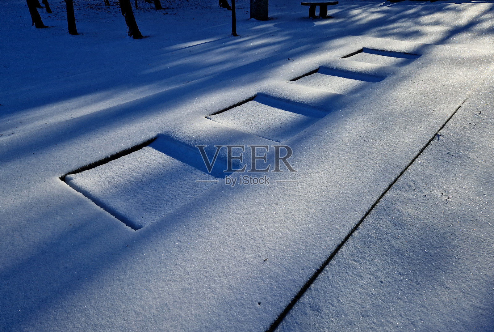 在学校操场的院子里,三个蹦床跳垫被埋在一个特殊的橡胶表面以下。周围是风景如画的后院的石墙上的木凳照片摄影图片