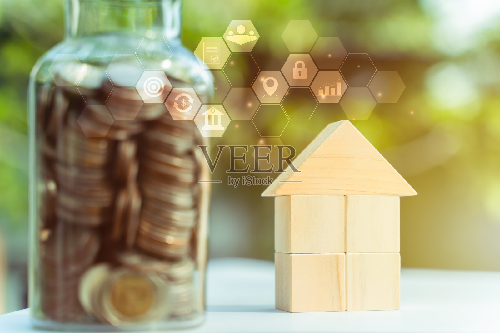 省钱的房子概念,必要的成本的房子,硬币在瓶子和木块房子模型。金钱和财务的房子概念。公园里的散景背景,晨光。照片摄影图片