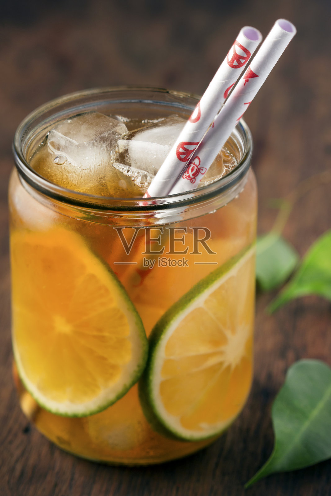 清爽的冰茶,用橙子片和冰块,可生物降解的吸管,用绿叶组成和制作,木制桌子,准备夏天照片摄影图片