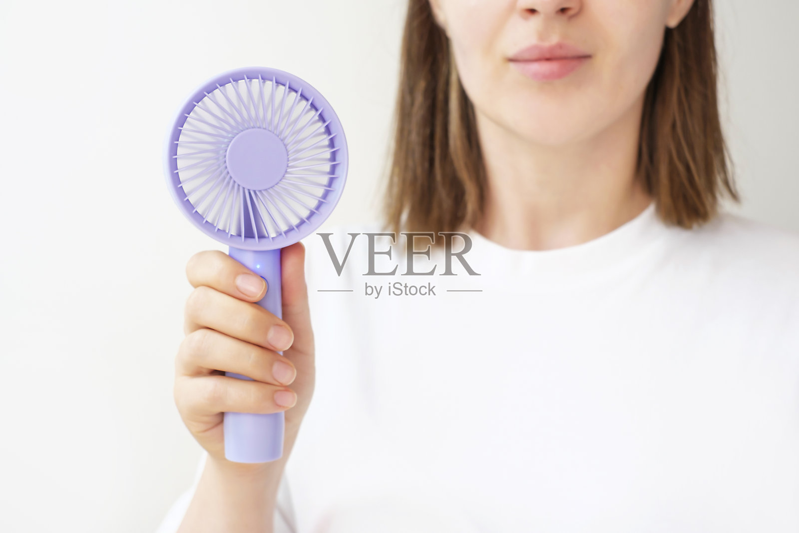 年轻女子手持迷你扇子,白色背景特写。照片摄影图片