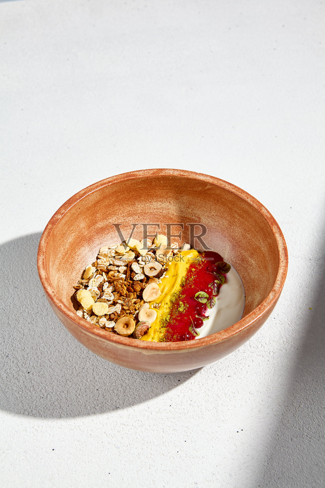 自制酸奶配格兰诺拉麦片、浆果慕斯和芒果片,装在一个质朴的碗里,阳光投下阴影照片摄影图片