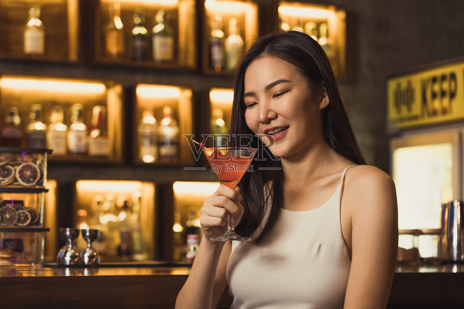 亚洲女人晚上在酒吧喝鸡尾酒,玩得很开心。照片摄影图片