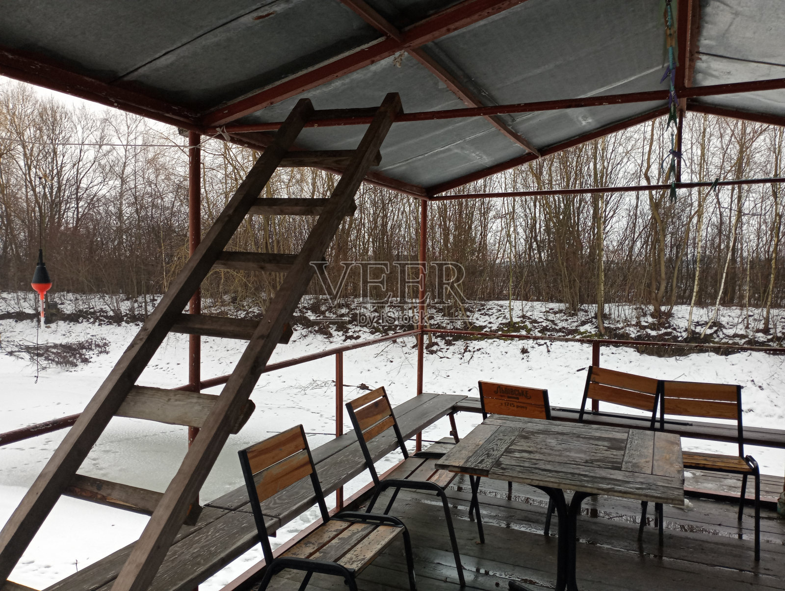 冬天池塘附近金属钓鱼棚里的木梯。冬天在有桌椅的地方享受大自然的乐趣。照片摄影图片