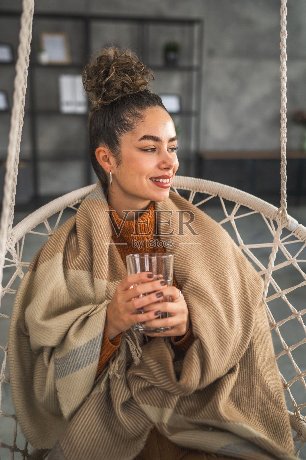 一个漂亮的年轻女子坐在家里拿着一杯水照片摄影图片