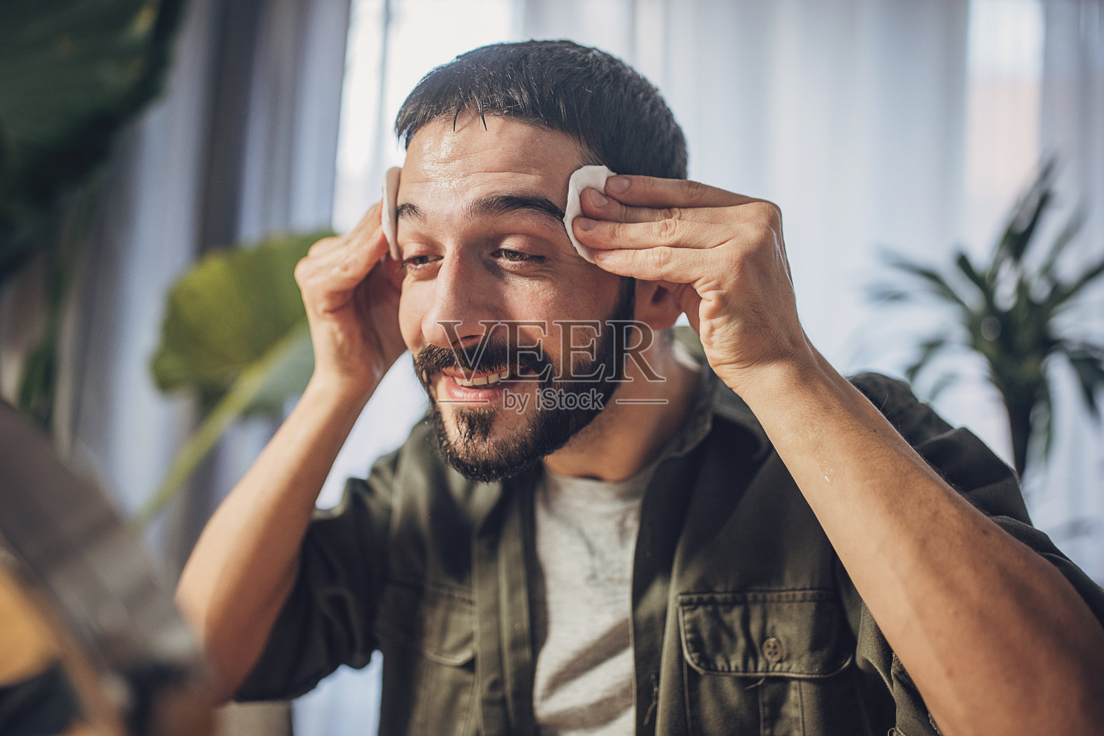 一名男子在面部护理过程中用化妆棉洗脸照片摄影图片