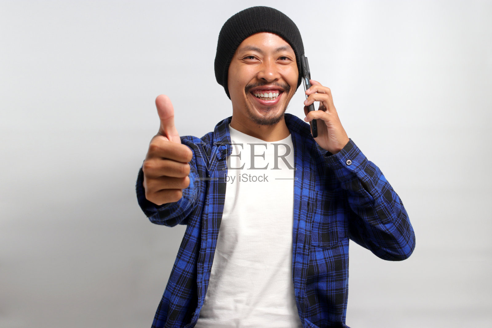 一名亚洲男子在接听电话时竖起大拇指照片摄影图片