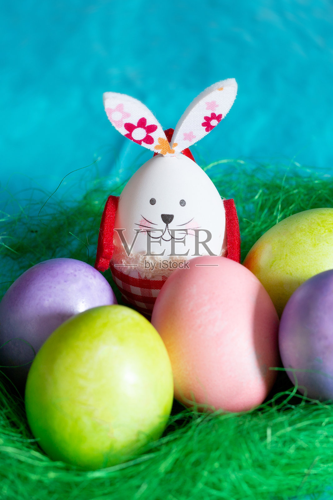 五颜六色的复活节彩蛋,绿色的窝和小兔子照片摄影图片