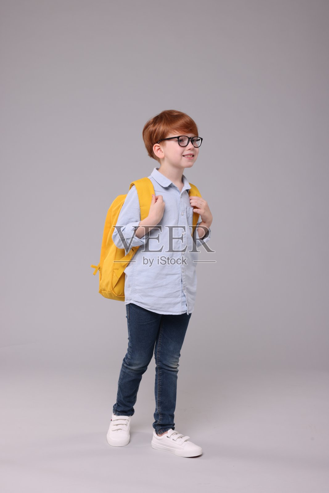 快乐的男生背着灰色背景的双肩包照片摄影图片