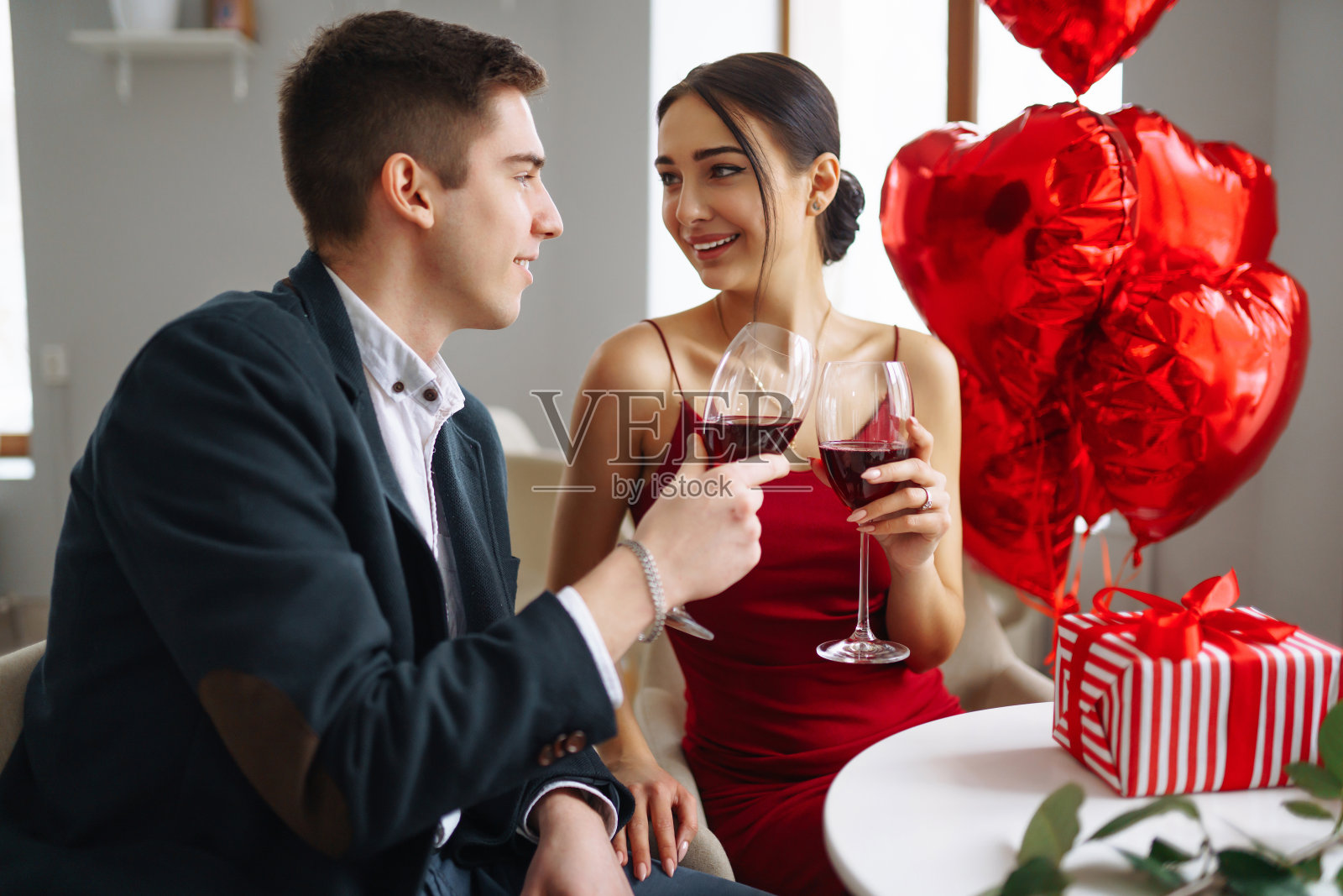 一对年轻的情侣在餐厅里喝着红酒庆祝情人节。关系,惊喜和爱的概念。照片摄影图片