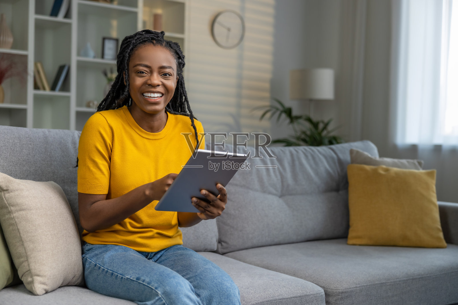 快乐的年轻非裔美国女人家里有平板电脑照片摄影图片