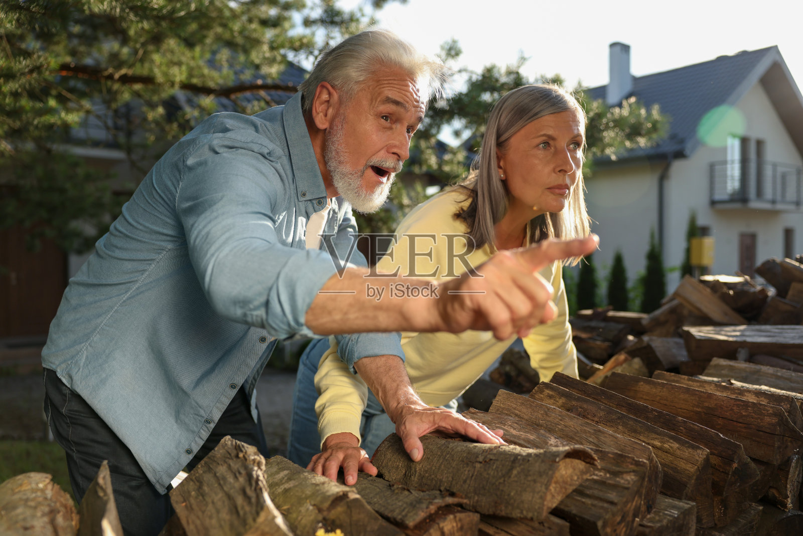 私人生活的概念。好奇的老夫妇在户外用柴火监视邻居照片摄影图片