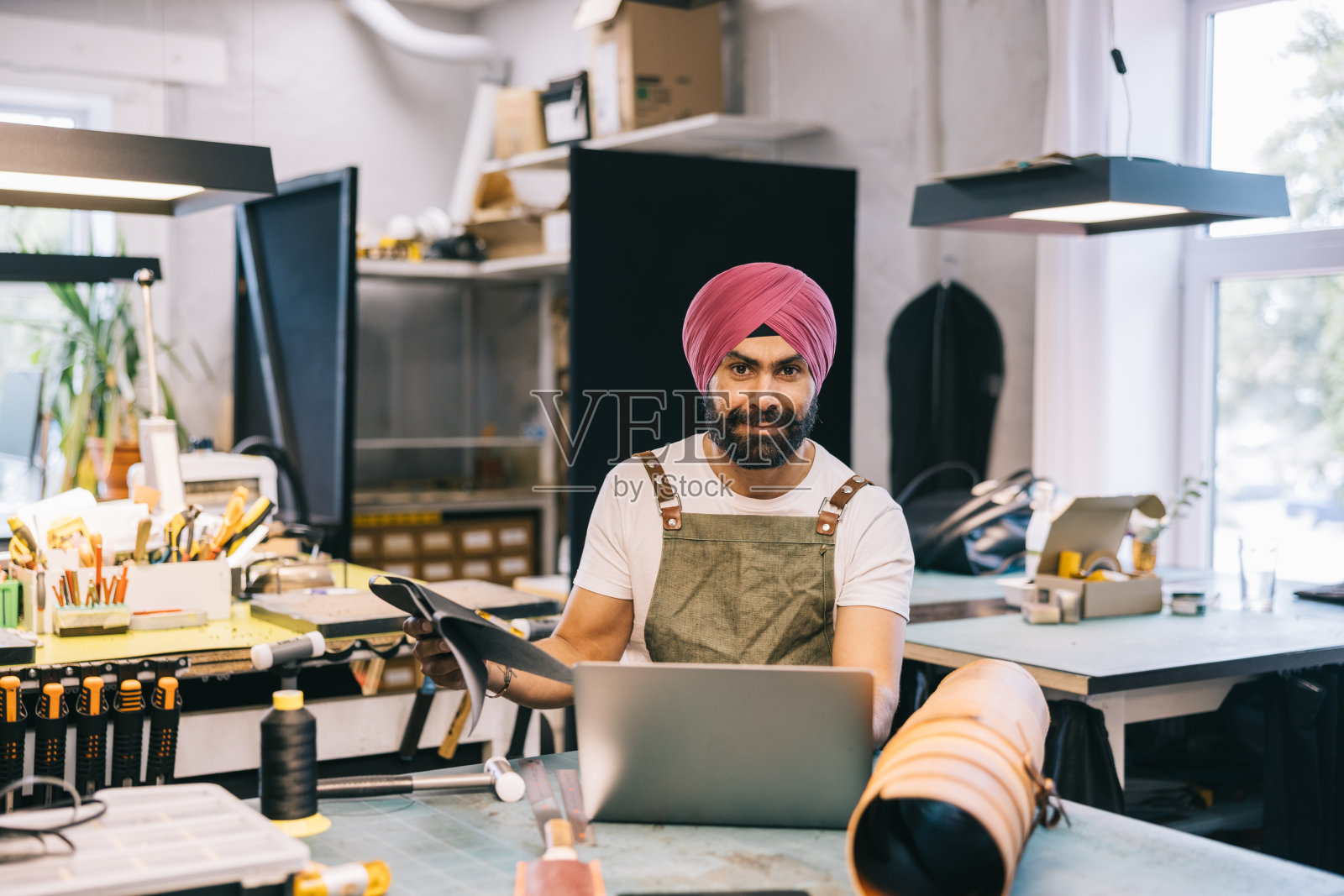 一位印度皮革工作室的老板正在用笔记本电脑管理客户订单照片摄影图片