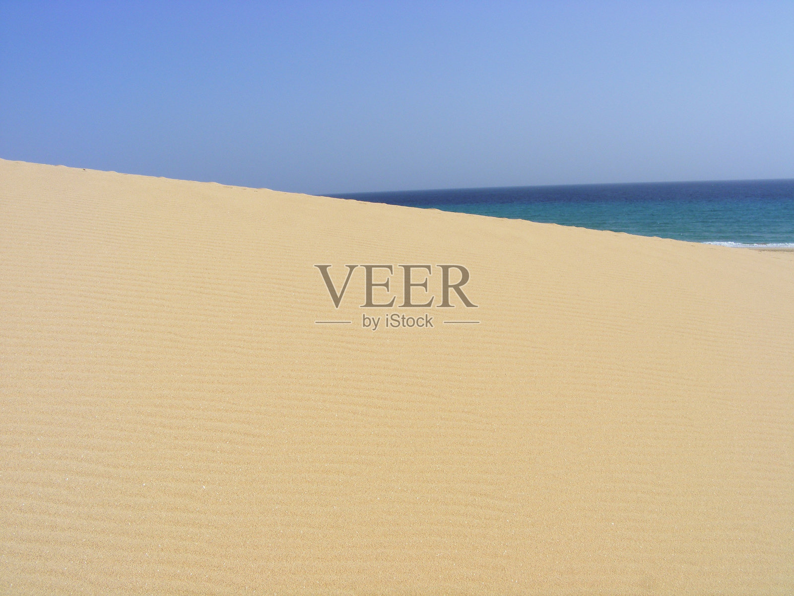 在富埃特文图拉岛上,沙丘、海洋和蓝天交汇在一起。照片摄影图片